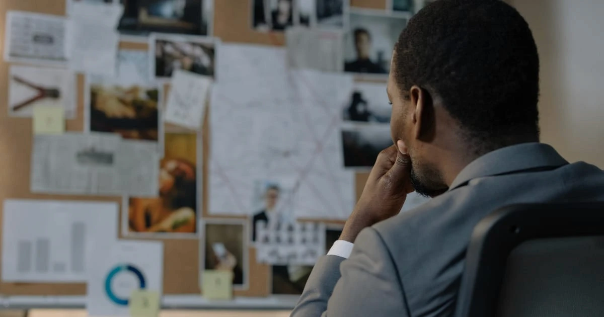 Man contemplating in front of a bulletin board.